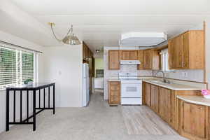 Kitchen featuring white appliances, light countertops, and wood finish cabinets