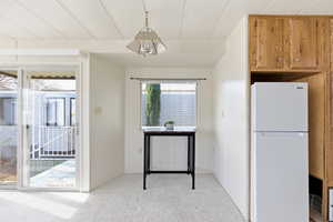 Kitchen featuring freestanding refrigerator, light carpet, and wood finish cabinets
