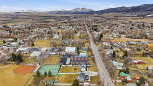 Aerial view of property and surrounding area featuring a mountainous background and nearby suburban area