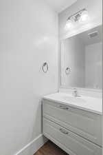1/2 Bathroom with vanity and dark wood-style flooring