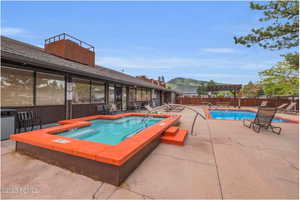 Community pool with a hot tub, a patio, a fenced backyard, and a pergola