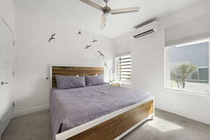 Carpeted bedroom featuring a wall mounted mini split and a ceiling fan