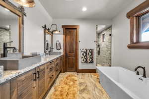 Bathroom with a stall shower, a freestanding bath, double vanity, and recessed lighting