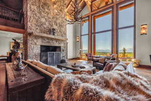 Living room with a fireplace, wood finished floors, a chandelier, a mountain view, and lofted ceiling