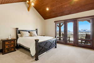 Bedroom with a high wooden beamed ceiling, a mountain view, access to exterior, light colored carpet, and a ceiling fan