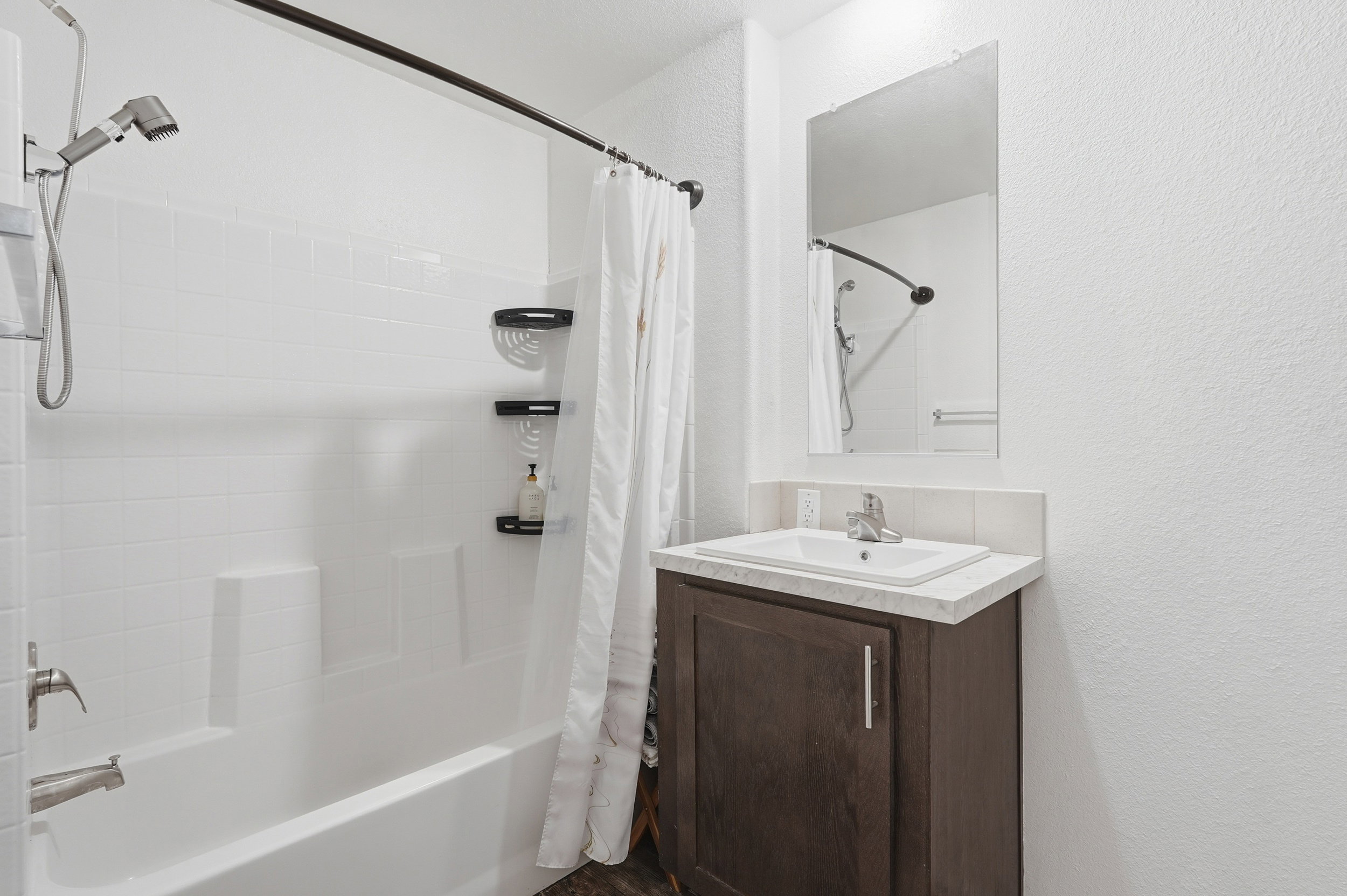 Bathroom with shower / tub combo with curtain, vanity, and a textured wall