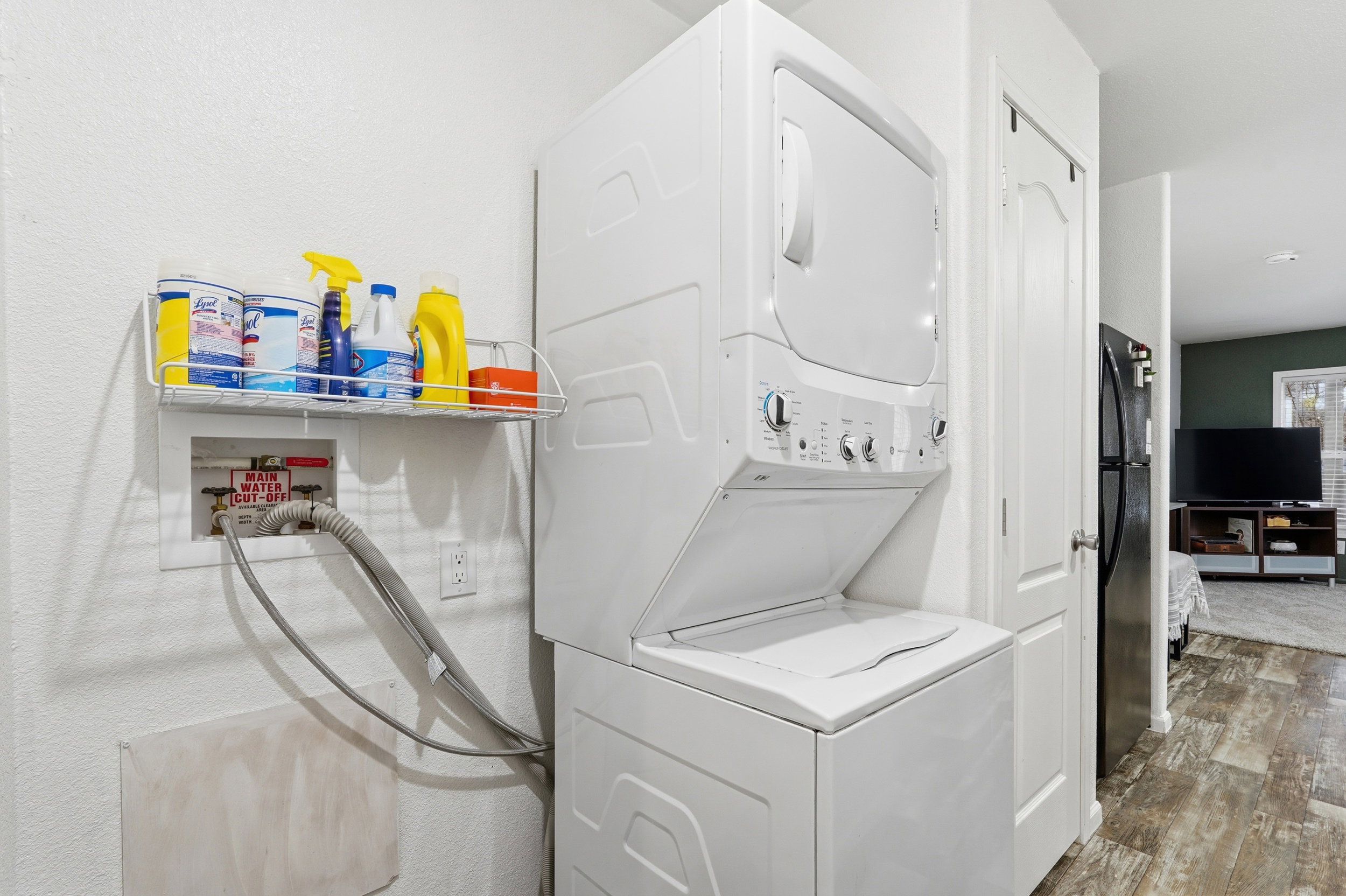 Laundry area featuring stacked washer and clothes dryer and wood finished floors