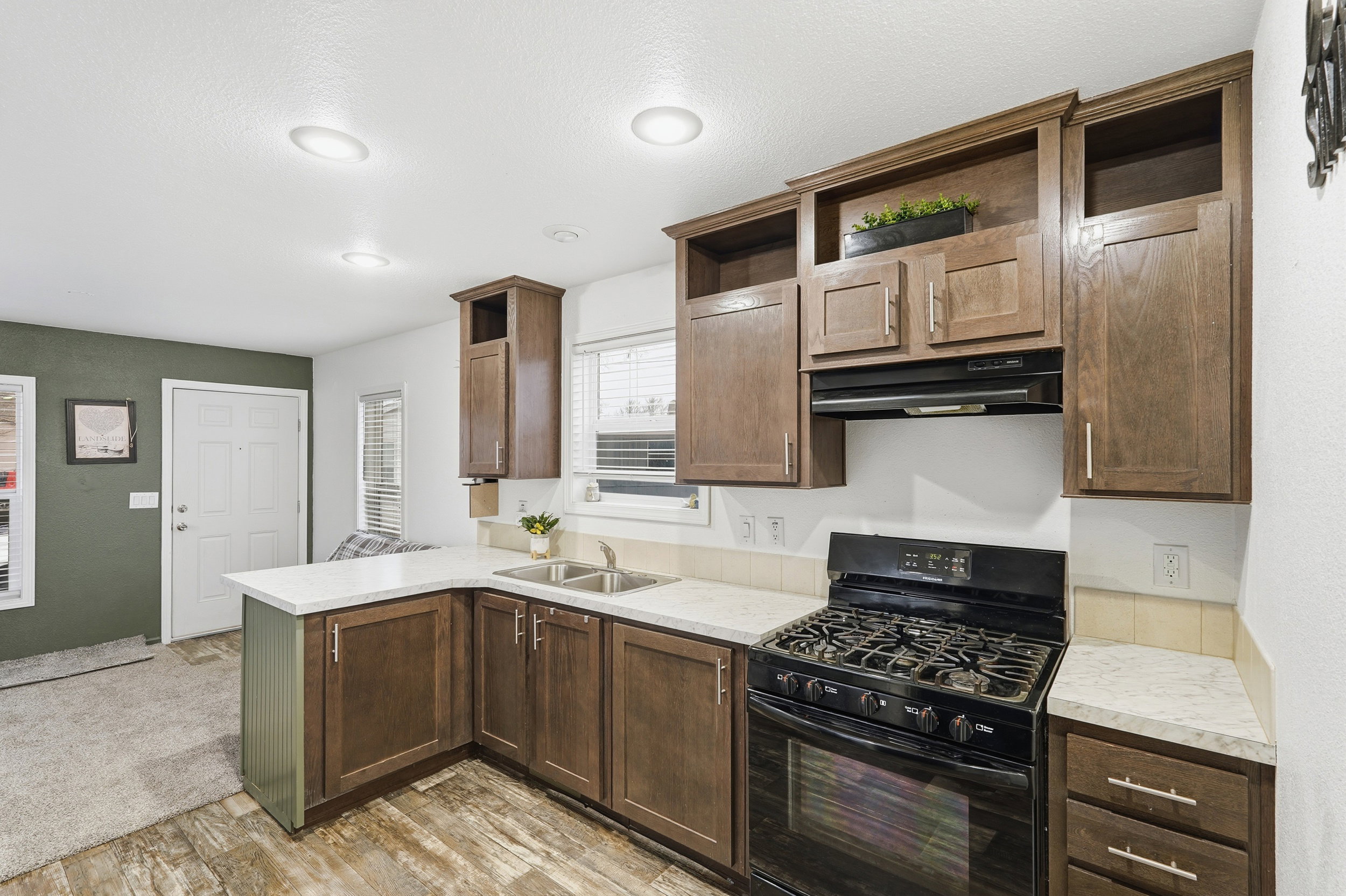 Kitchen with black gas range, open shelves, light countertops, and a peninsula
