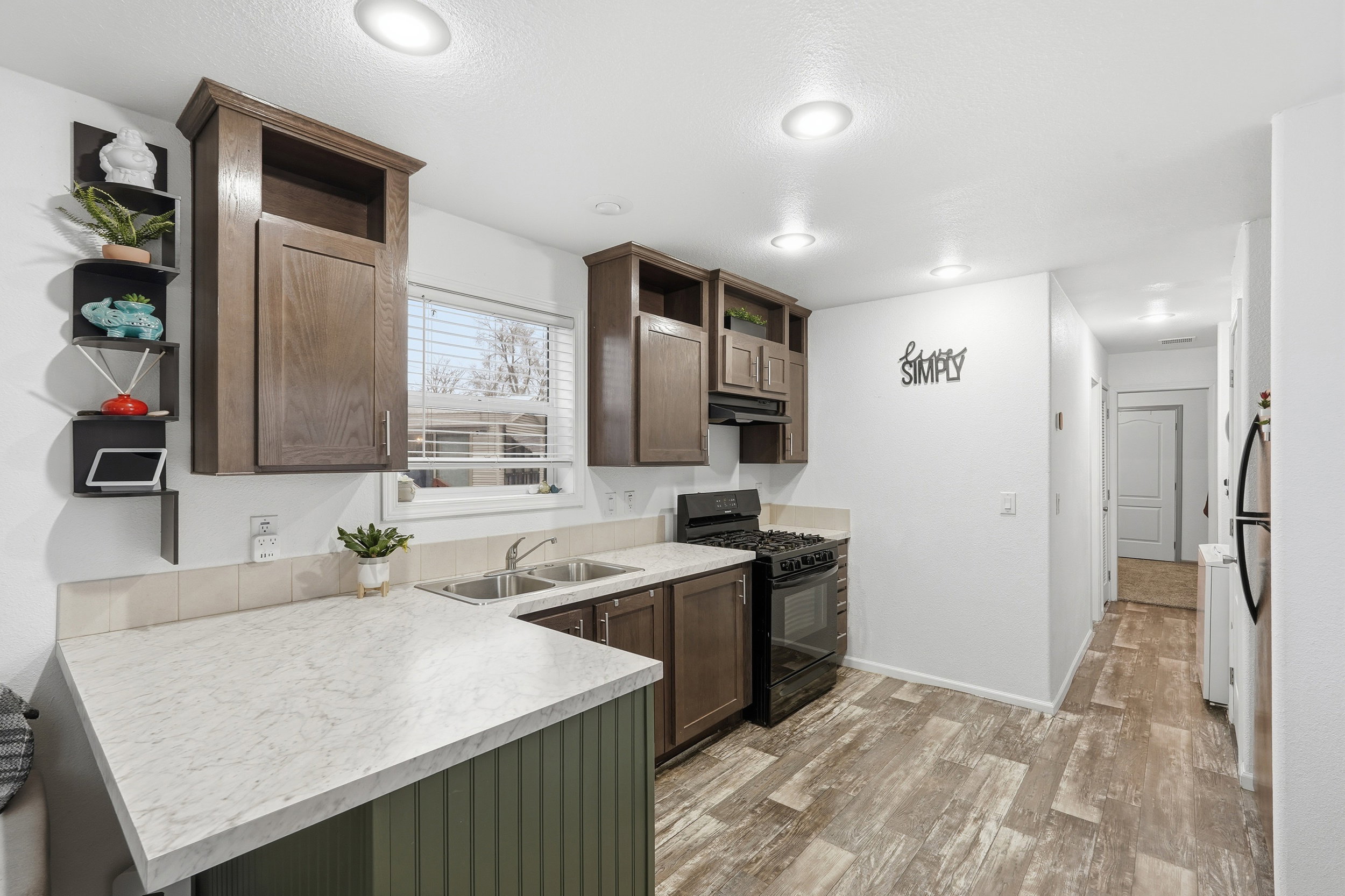 Kitchen featuring open shelves, dark wood finish cabinets, gas stove, light countertops, and light wood-style flooring