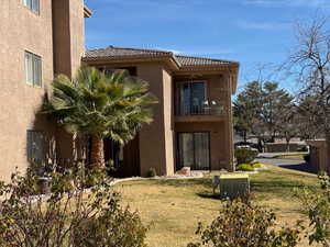 Rear view of property with a balcony, stucco siding, and a yard