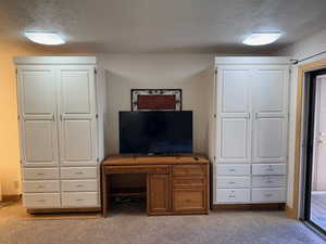 Bedroom with a textured ceiling and light carpet