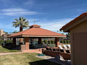 Back of house with a patio, a tile roof, brick siding, a gazebo, and a lawn