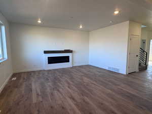 Unfurnished living room with dark wood finished floors, a fireplace, a textured ceiling, and recessed lighting