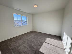 Spare room with dark carpet and baseboards