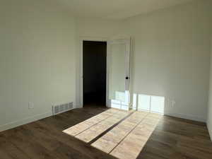 Empty room featuring dark wood-style floors and baseboards