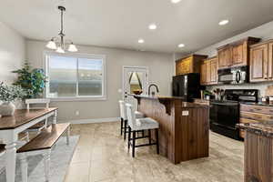 Kitchen and Dining areas with a kitchen breakfast bar, black appliances, a kitchen island with sink, and dark granite countertops