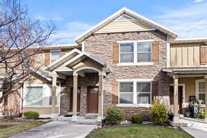 Craftsman-style home featuring stone siding, stucco siding, and a front yard