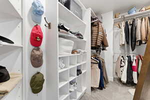 Walk in closet with light colored carpet