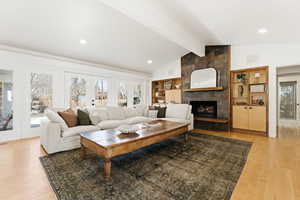 Living room featuring french doors, healthy amount of natural light, built in shelves, light wood finished floors, and beamed ceiling