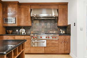 Kitchen with wood finish cabinetry, dark stone counters, a warming drawer, and stainless steel appliances