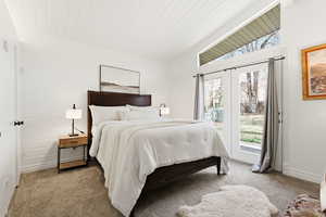 Carpeted bedroom featuring access to outside and a vaulted wooden ceiling