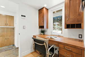 Home office featuring built in desk, light stone finish flooring, and recessed lighting