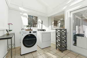 Laundry room featuring lofted ceiling, independent washer and dryer, and light tile patterned floors