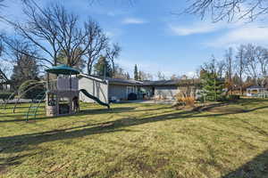 Rear view of property featuring a patio area, a playground, and a lawn
