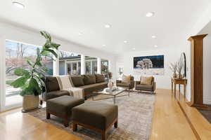 Living room featuring ornamental molding, decorative columns, light wood-type flooring, and recessed lighting