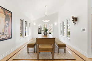 Dining room with vaulted ceiling, healthy amount of natural light, and light wood-type flooring
