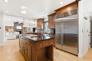 Kitchen with stainless steel appliances, wood finish cabinets, a fireplace, a center island with sink, and open floor plan