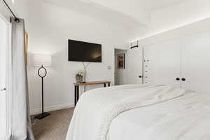 Carpeted bedroom with a closet and lofted ceiling with beams