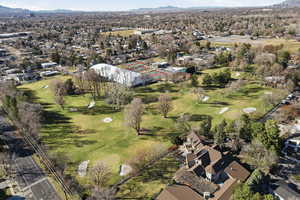 Aerial view of property and surrounding area with mountains, nearby suburban area, and a golf course