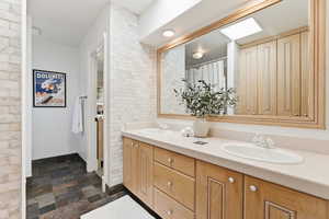 Bathroom featuring double vanity, stone finish floors, and curtained shower