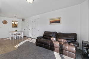 Living room with carpet floors, tile patterned flooring, and hanging lights