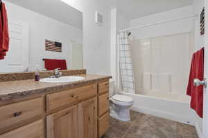 Bathroom with vanity, shower / tub combo, and dark tile patterned floors