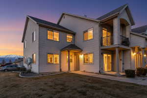 View of front of property with a balcony, a shingled roof, and a front yard