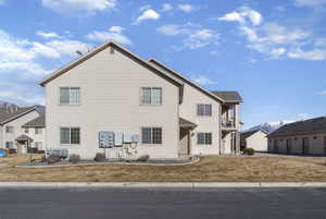 View of front facade featuring a balcony, a mountain view, and a front lawn