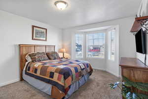 Carpeted bedroom featuring baseboards and a textured ceiling