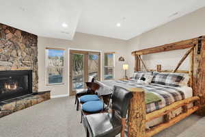 Carpeted bedroom with a fireplace and access to outside