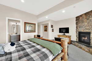 Bedroom with a stone fireplace, carpet, connected bathroom, recessed lighting, and a closet