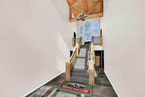 Stairway featuring a high wooden ceiling, stone finish flooring, and hanging lights
