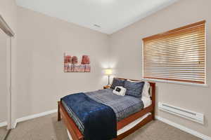 Bedroom featuring a baseboard radiator, light colored carpet, and a closet