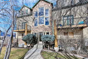 View of front of home featuring stone siding and a balcony