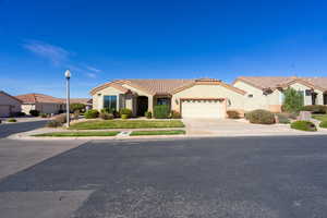 Mediterranean / spanish home featuring a garage, stucco siding, a tile roof, driveway, and a residential view