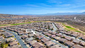 Aerial perspective of suburban area with a mountain backdrop and a golf club