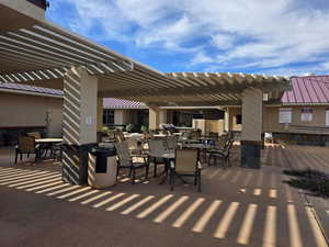 View of patio at community center with outdoor dining area and a pergola