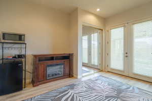 Doorway with french doors, wood finished floors, electric fireplace and recessed lighting