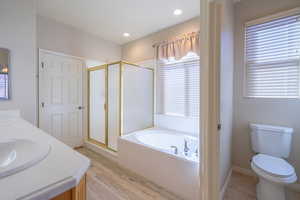 Full bathroom with a shower stall, double vanity, a bath, and LVP flooring