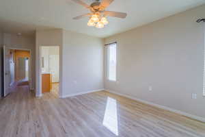 Primary  bedroom with light wood-type LVP flooring, ceiling fan, and connected bathroom